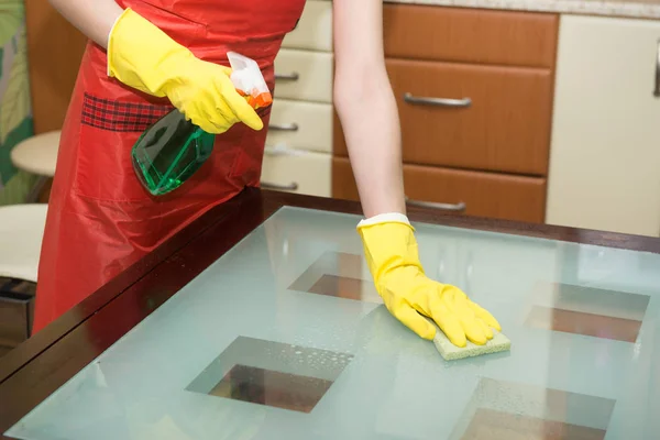 管家洗涤玻璃桌在与清洁喷雾和海绵佩带手套在公寓里 — 图库照片