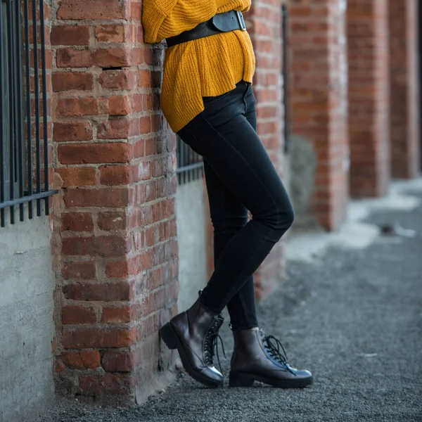 Female spring outfit with black skinny slim jeans leather casual boots, belt and knitted sweater.