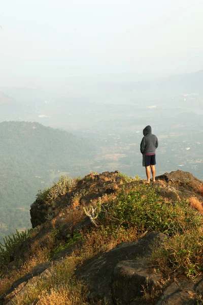 Jovem de pé no topo de uma montanha e desfrutando de vista para o vale — Fotografia de Stock