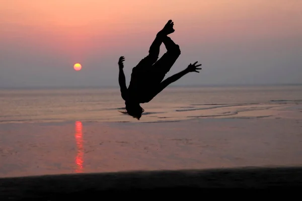Naplemente és sziluettje egy táncos a strandon — Stock Fotó