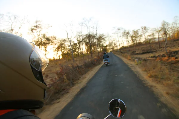 Biker driving a motorcycle rides along the asphalt road.