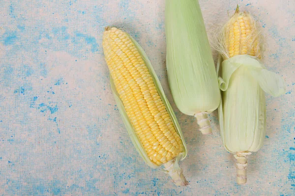 Färsk majs på majskolvar på textur bakgrund, närbild, ovanifrån — Stockfoto
