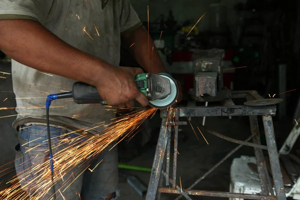 Metal works. Electric wheel grinding on steel structure in factory