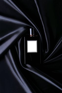 İpek katlanmış kumaş arka planında parfüm şişesi. Paket tasarımı taklit ediliyor. Koku, kozmetik güzellik ürünü reklam afişi.. 