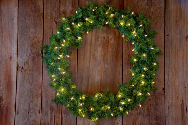 Christmas small green wreath with cones at wood board. Copy space