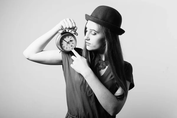 目覚まし時計を表示してカメラの帽子でエレガントな美しい若い女性の黒と白の肖像画 — ストック写真