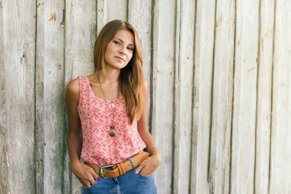 Fashion young blond woman in pink Tshirt over pale wooden background — Stock Photo, Image