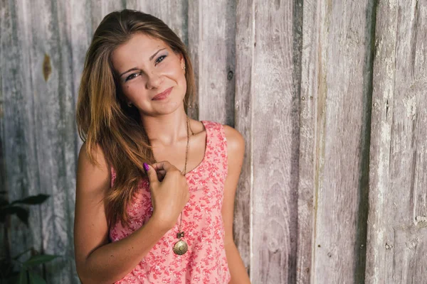 Fashion young blond woman in pink Tshirt over pale wooden background — Stock Photo, Image