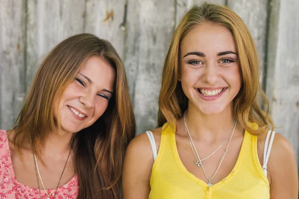 Two happy female friends smiling over pale wooden background — Stock Photo, Image