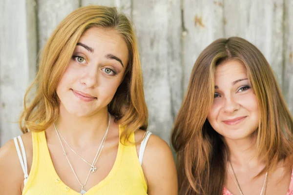 Two happy female friends smiling over pale wooden background — Stock Photo, Image