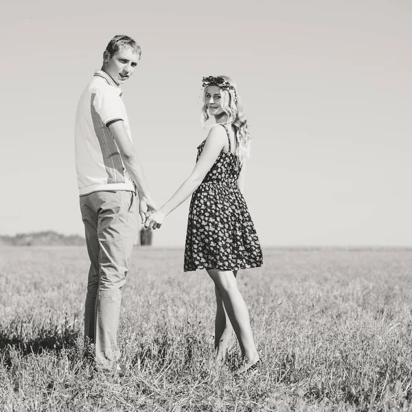 Молода пара ходить у полі з квітами на сонячному світлі в чорно-білому — стокове фото