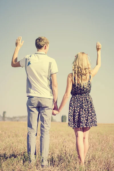 Happy smiling young hippie couple holding hands outdoors from back — Stock Photo, Image