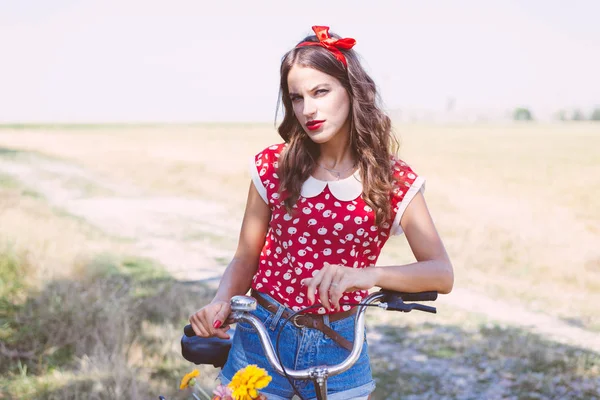 サイクリング 明るい青い夏空コピー空間イメージの下のフィールドで若い美しいブルネット ピンナップ女性 — ストック写真
