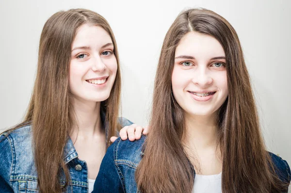 特写肖像的两个美丽的年轻女子长黑头发和自然化妆穿牛仔裤衬衫快乐的微笑看着相机 — 图库照片