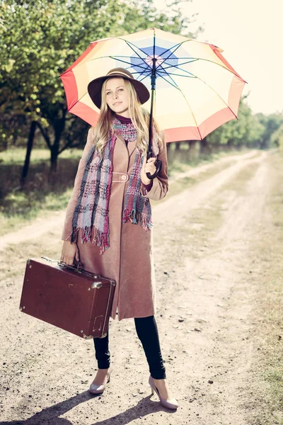 Vrouw alleen met vintage koffer liften op lege weg buiten — Stockfoto