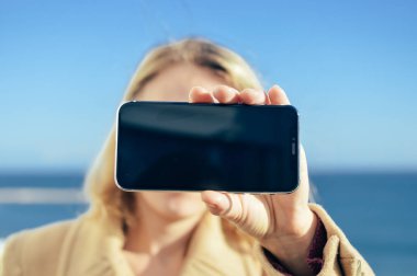 Mobil akıllı telefon kullanarak tutan kişinin closeup görünümü. Güneşli gün açık. Arka yüzünde en iyi görünüm görüntüsü manifatura, konuşurken, Gps navigasyon, modern iletişim teknoloji tasarım arka plan sahte