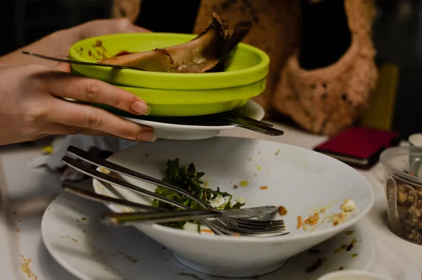 汚れたお皿や完成した夕食のテーブル背景から食器を取る女性の手にクローズ アップ ウィンドウ ボケ空間を抽象化完了のきれいな時間を食べて — ストック写真