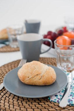 Taze kabuklu ekmek ve gri tabakta bir bardak meyve suyu ile tabak