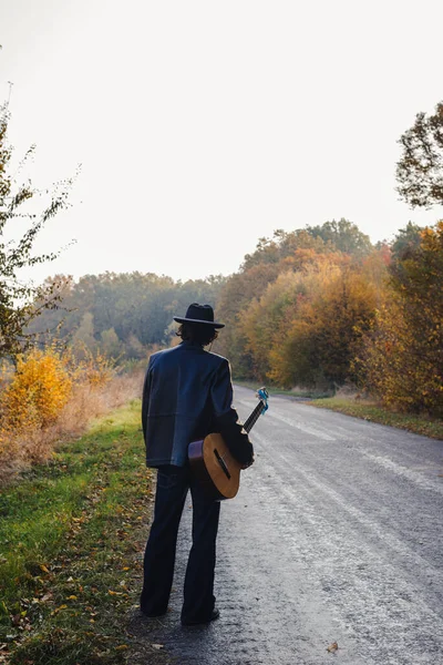 Одинокий Гитарист Смотрит Пустую Проселочную Дорогу Осенью — стоковое фото