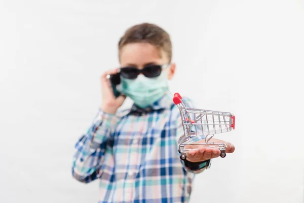 Kleine Schooljongen Draagt Wegwerpmasker Zonnebril Houdt Kleine Winkelwagentje Mobiele Telefoon — Stockfoto