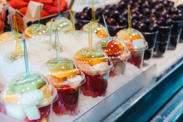 Buah Salad diatur dalam cangkir plastik di warung pasar dengan garpu kecil di dalam, takeaway snack — Stok Foto