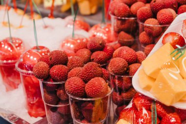 Bir markette satılık taze kırmızı liçi yığını. Plastik bardakta..