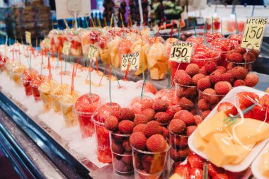 Meyve salatası plastik bardaklara yerleştirilmiş içinde çatal olan bir market tezgahında, sağlıklı atıştırmalıklar.