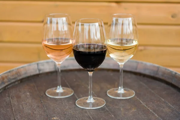 木製の背景に赤とバラのワインと3つのワイングラス — ストック写真