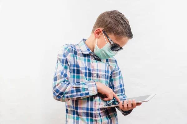 使い捨てのマスクとサングラスをかけ 白い背景にタブレットを持っている学校の少年 家庭教育の概念 — ストック写真