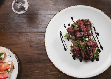 Füme etli bruschetta seti, kaba ahşap arka planda roka. Üst görünüm