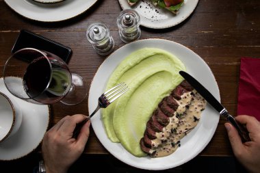 Tahta bir masada dilimlenmiş etle patates püresi.