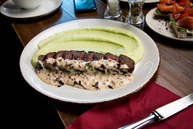 Tahta bir masada dilimlenmiş etle patates püresi.