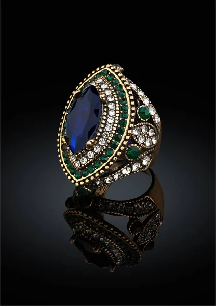 Anel dourado com pedras preciosas e diamantes sobre fundo preto — Fotografia de Stock
