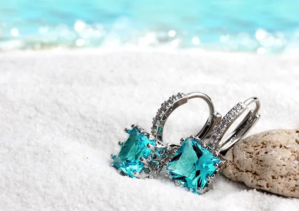 Pendientes de joyería con aguamarina sobre fondo de playa de arena, suave —  Fotos de Stock