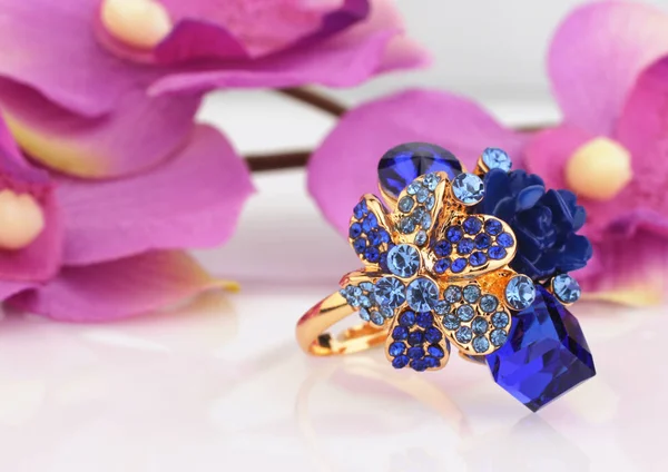 Bague à bijoux avec gemmes bleues et fond de fleur — Photo