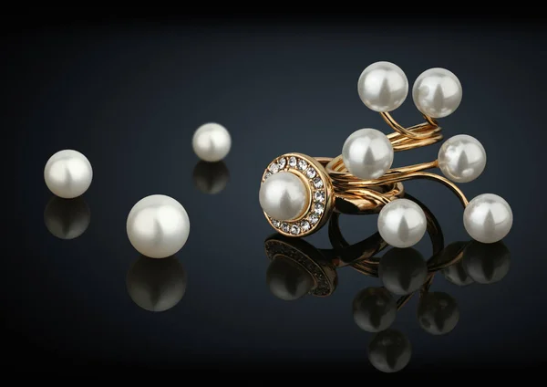 Zlaté prsteny s diamanty a perlami na černém pozadí — Stock fotografie