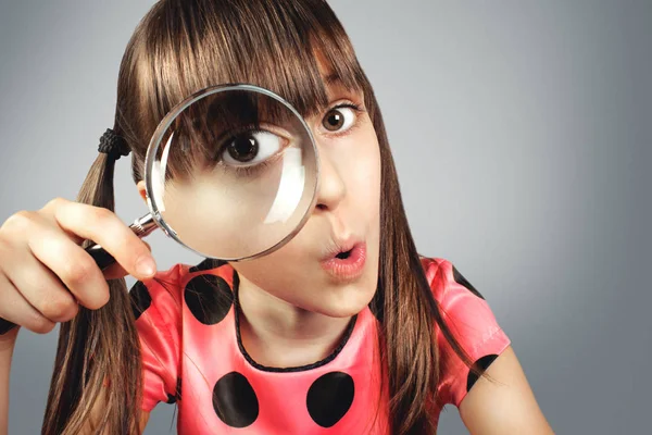 Amazed child girl looking through magnifying glass, searching co — Stock Photo, Image