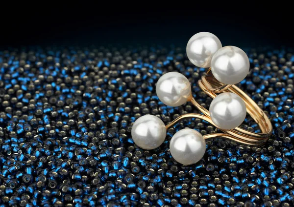 Golden jewelry ring with pearls on dark blue beads — Stock Photo, Image