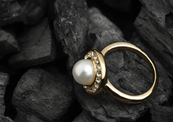 Juwelen ring with diamond en pearl op zwarte kolen achtergrond, co Stockfoto