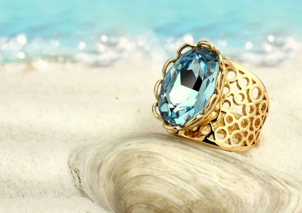 Anillo de joyería con aguamarina en la playa de arena de verano Imágenes de stock libres de derechos