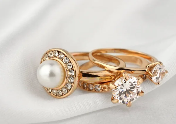 Κοσμήματα δαχτυλίδια με διαμάντια και μαργαριτάρι σε λευκό πανί, απαλή εστίαση — Φωτογραφία Αρχείου