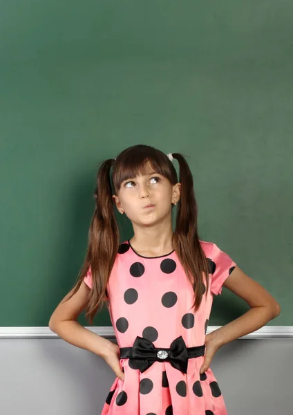 Pensive child girl near blank school blackboard — Stock Photo, Image