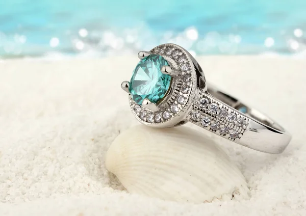 Bague à bijoux avec gemme aquamarine propre sur fond de plage de sable — Photo