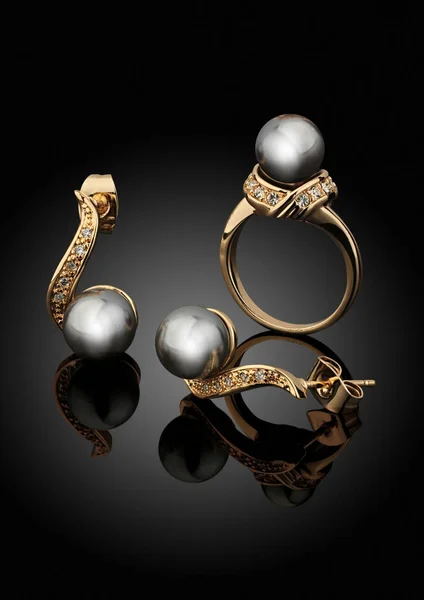 Set di gioielli dorati con perle su sfondo nero con riflessi — Foto Stock