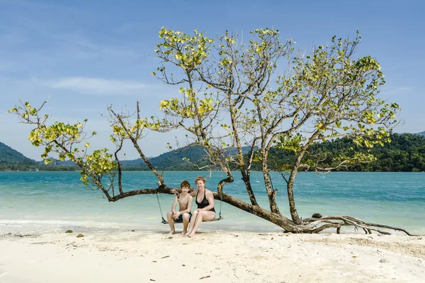 Mother and son sitting on a  swing at the idyllic beach — Stock Photo, Image