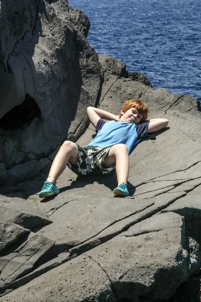 Happy boy lies on the rock — Stock Photo, Image