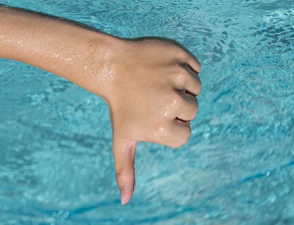Palec dolů projevem mladý muž, teenager s modrou vodou jako pozadí — Stock fotografie
