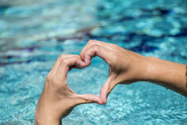 Genç adam tarafından ellerin kalp şeklinde aşk işaretleri gösteriyor — Stok fotoğraf