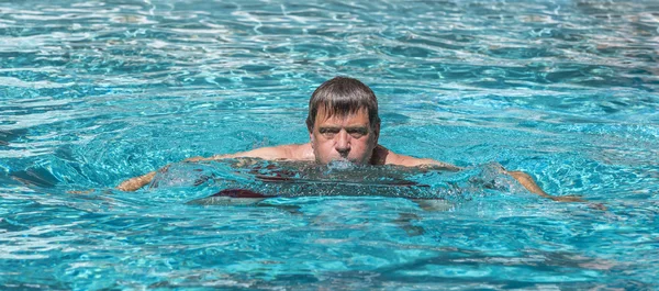 Homem bonito gosta de nadar na piscina — Fotografia de Stock