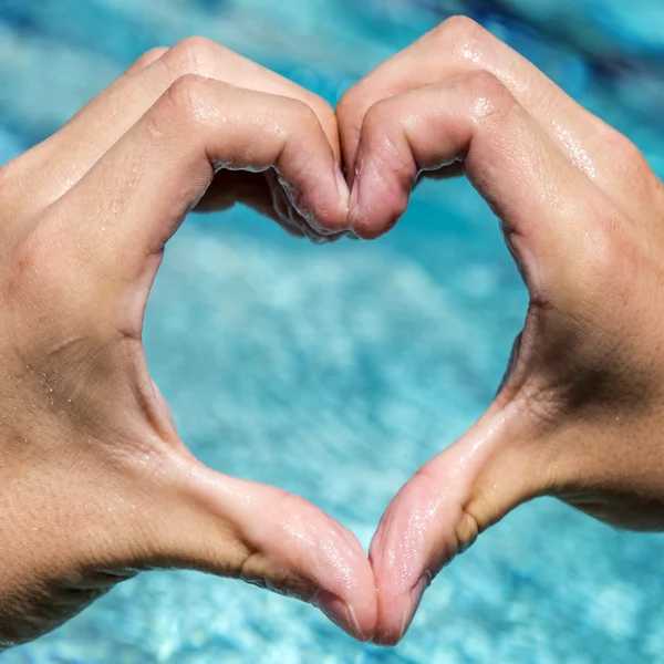 Young man shows love sign with heart shape formed by hands — Stock Photo, Image